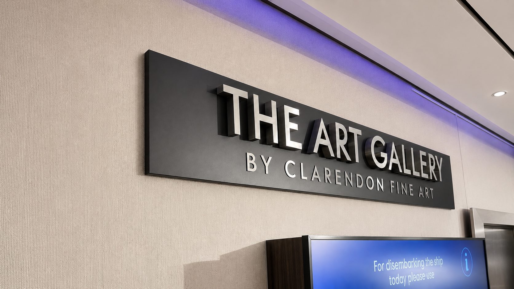 Sign reading 'THE ART GALLERY BY CLARENDON FINE ART' mounted on a beige wall with blue ambient lighting above.