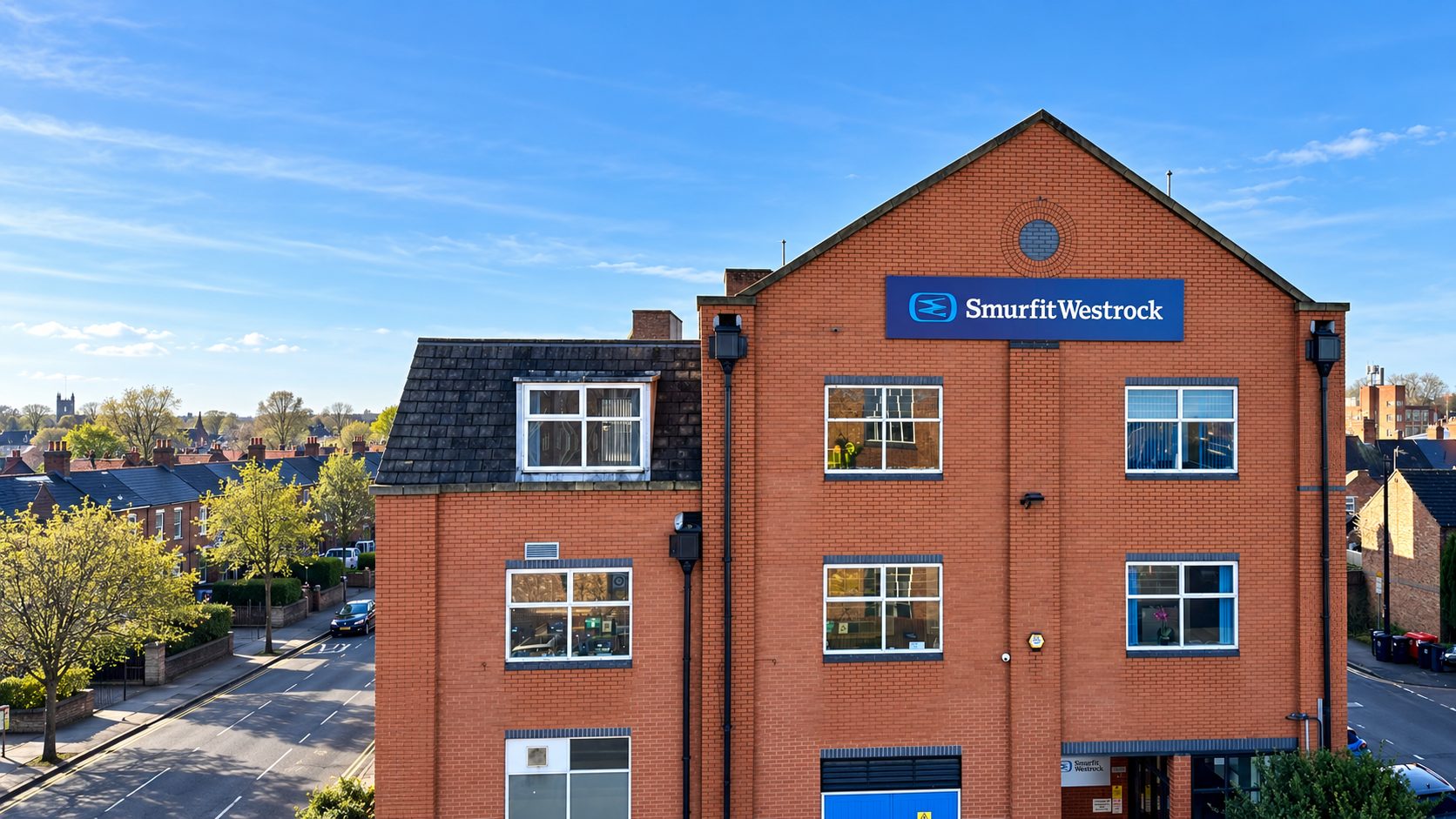 Brick office building with a blue Smurfit Westrock sign on the facade, overlooking a tree-lined street.