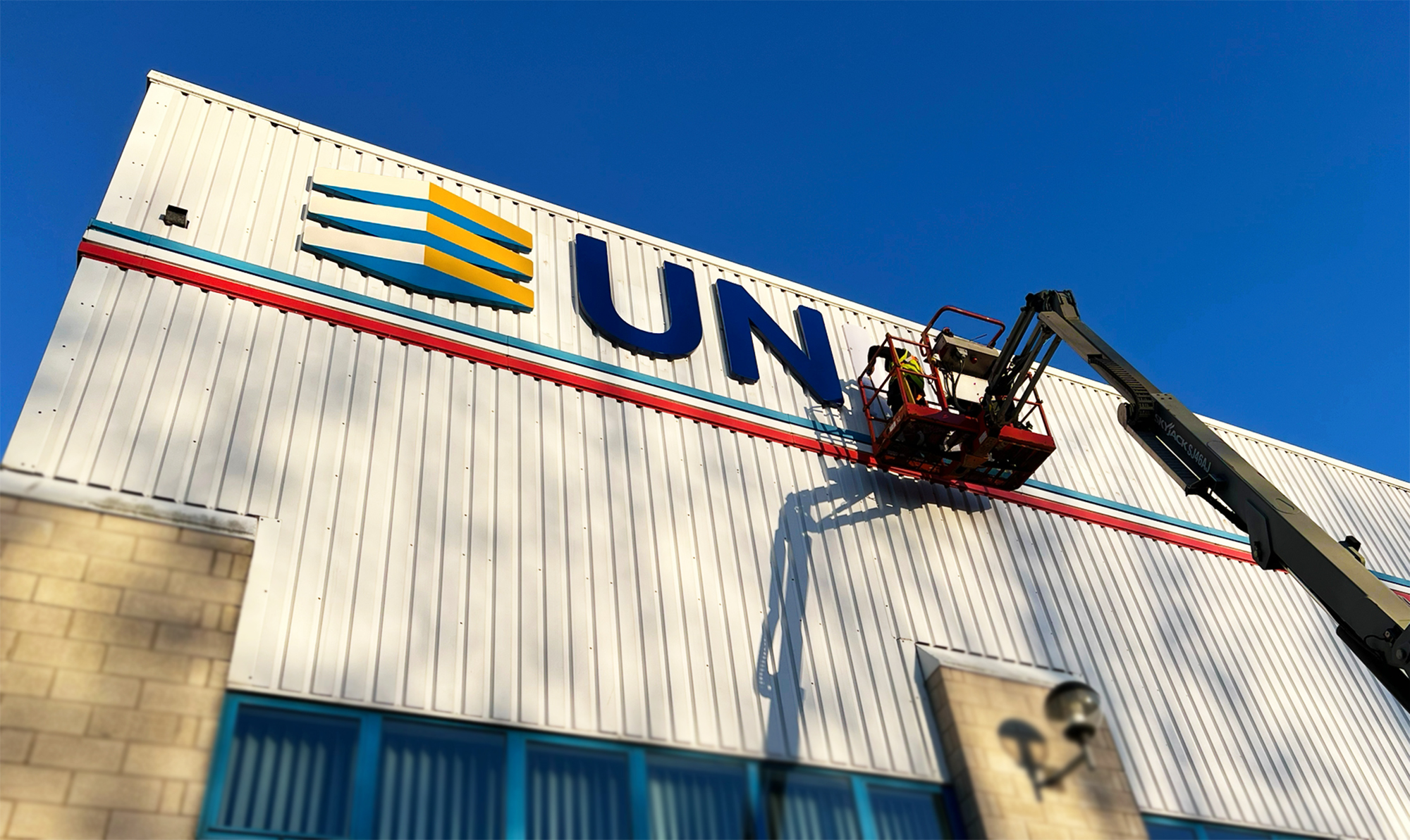 A blue building facade with a prominent metallic, 3D spiral logo reflecting