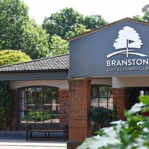 Branston Golf & Country Club sign on a blue-gray wall with a white tree logo and brick columns.