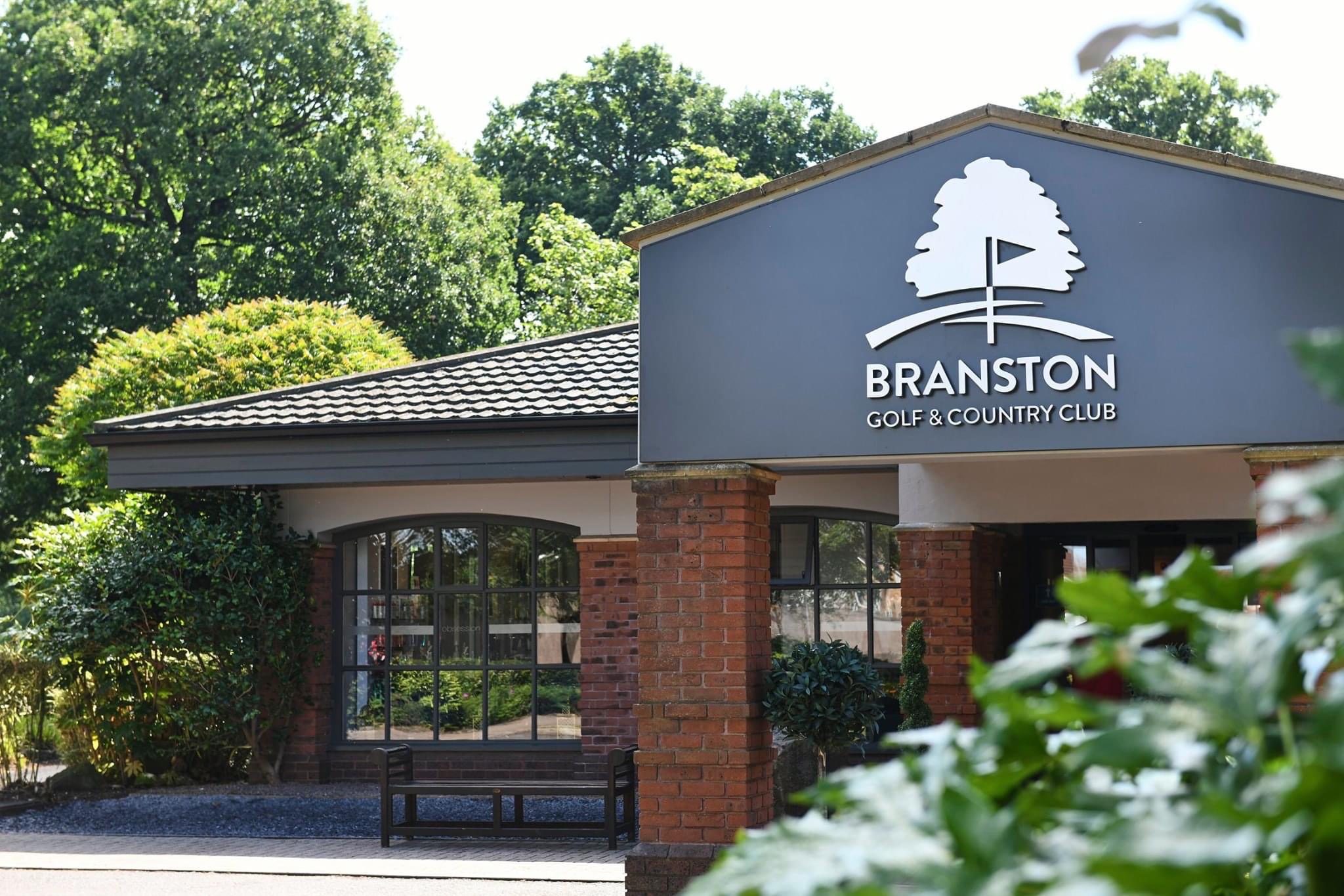 Branston Golf & Country Club sign on a blue-gray wall with a white tree logo and brick columns.