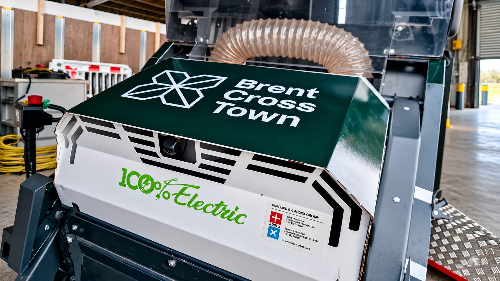 Industrial machine in a workshop with Brent Cross Town branding and a 100% Electric logo visible on the unit.
