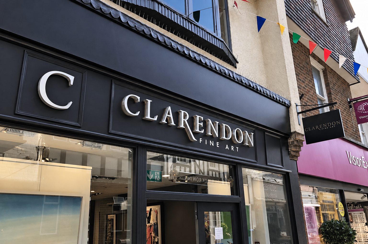 Black storefront signage reading 'CLARENDON FINE ART' with large 'C' logo and gallery windows reflecting street life