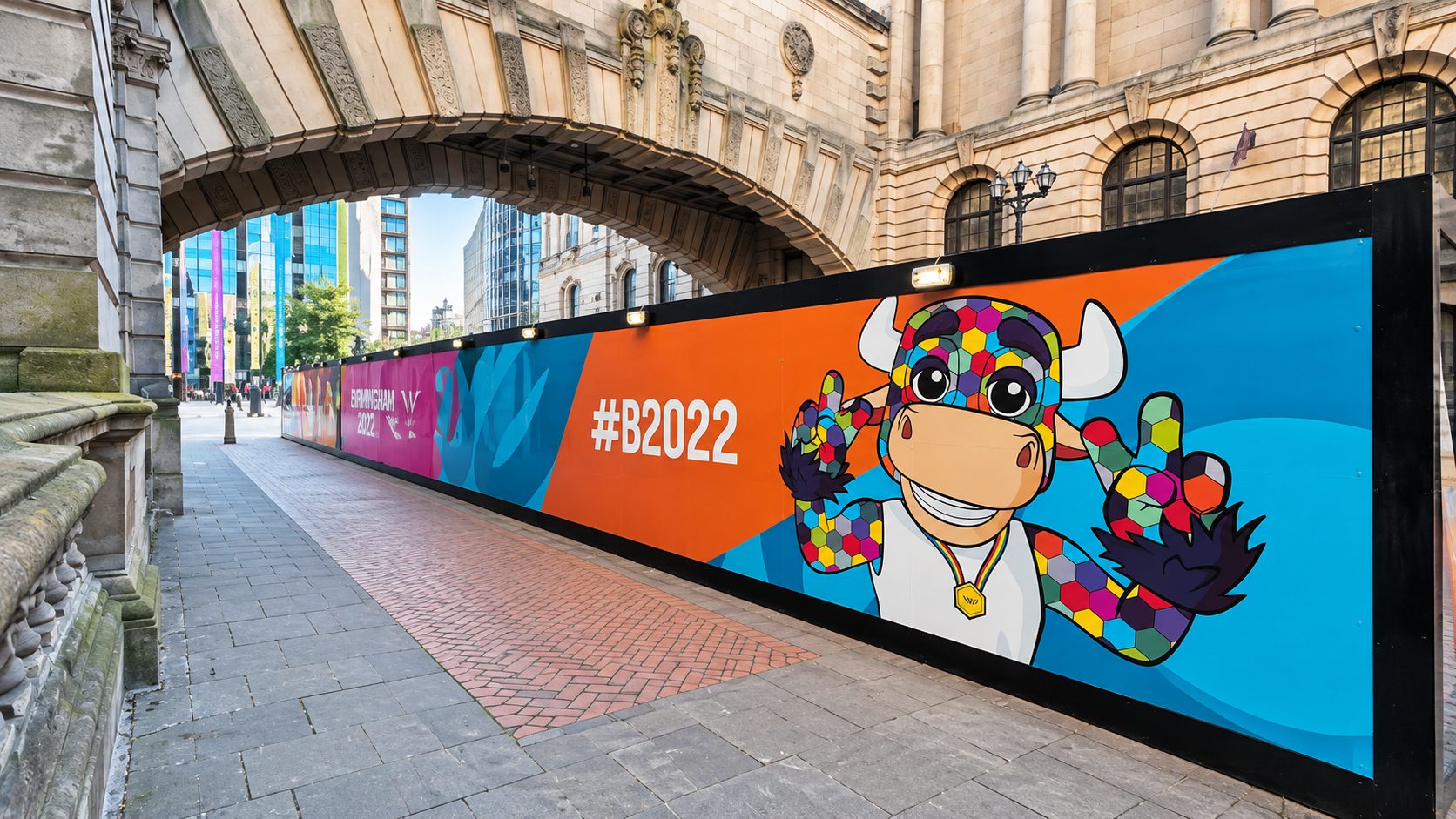 Colorful mural on a city construction barrier under a historic arch, featuring a mosaic-patterned bull mascot and '#B2022' text.