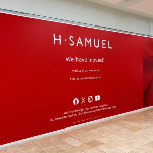 H. Samuel red banner announcing the move: 'We have moved!' with directions to visit the new store and find us online in a mall corridor.