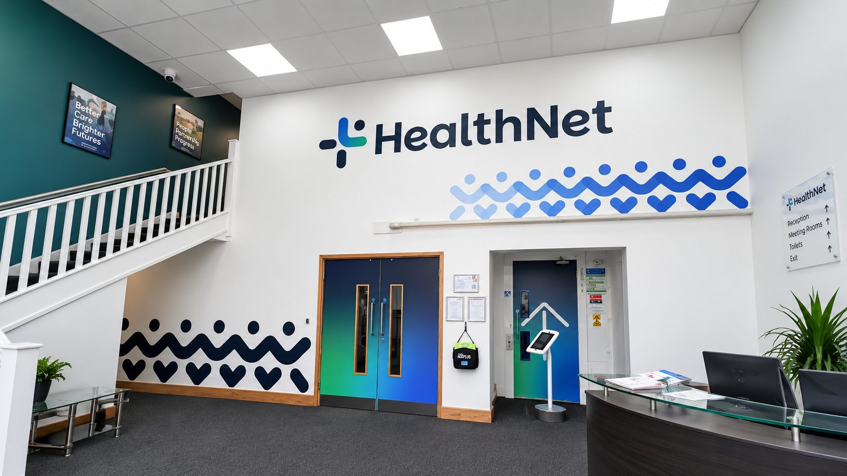 HealthNet reception area with a large logo on white wall and a blue wave pattern, and a curved front desk to the right.