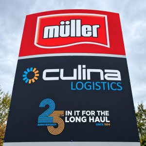 Outdoor sign featuring Müller logo above Culina Logistics branding, with a blue‑orange 25th anniversary graphic and the text 'In it for the long haul'.
