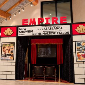 The Empire cinema facade with red letters, vintage marquee showing Casablanca and The Maltese Falcon, red curtains open to a small stage.