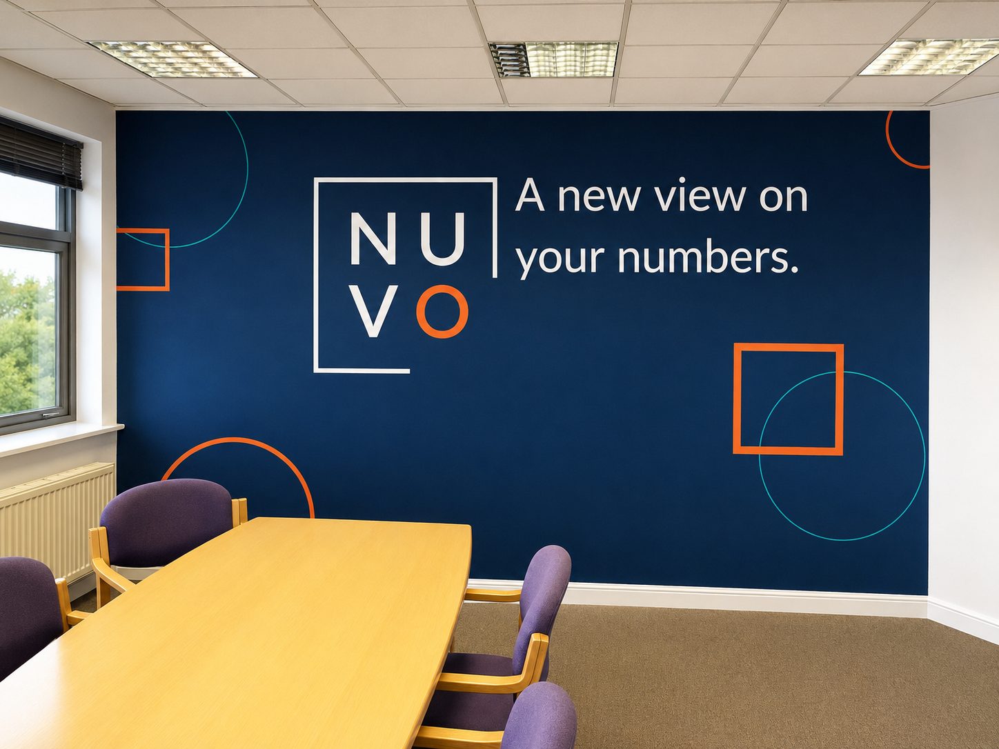 Conference room with a navy wall displaying the NUVO branding—letters inside a white frame and the slogan 'A new view on your numbers' with orange and teal geometric shapes nearby.