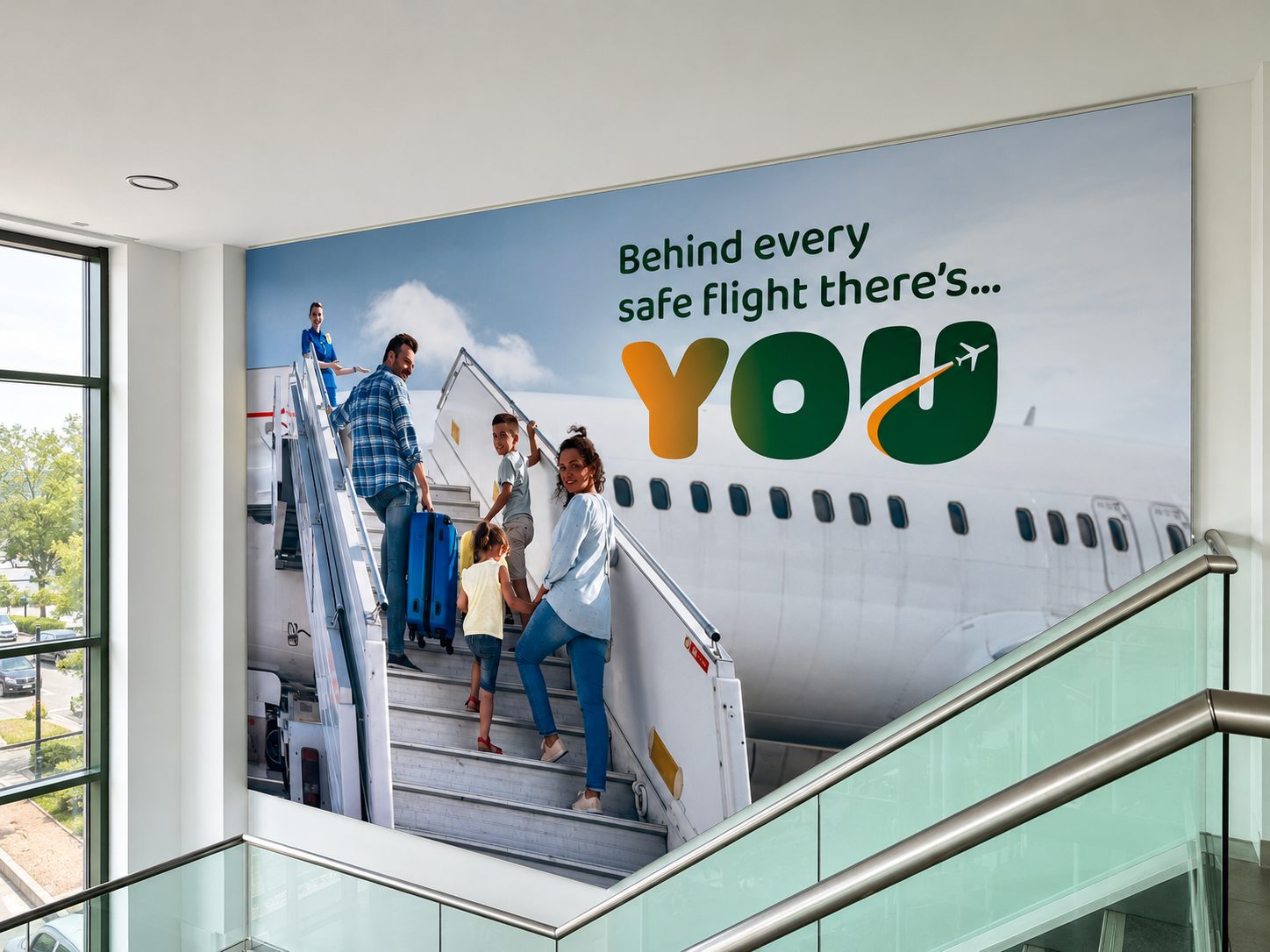 Poster showing a family boarding an airplane with the message 'Behind every safe flight there's... YOU' on a large wall banner.