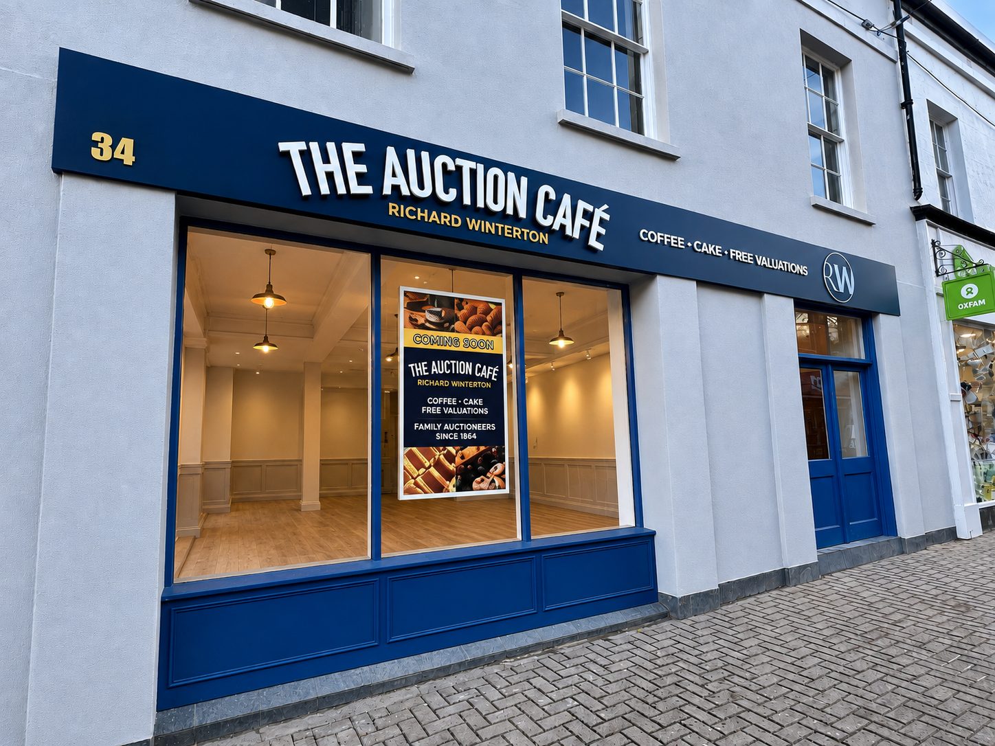 Front view of The Auction Café storefront with blue signage, street number 34, and a poster in the window.