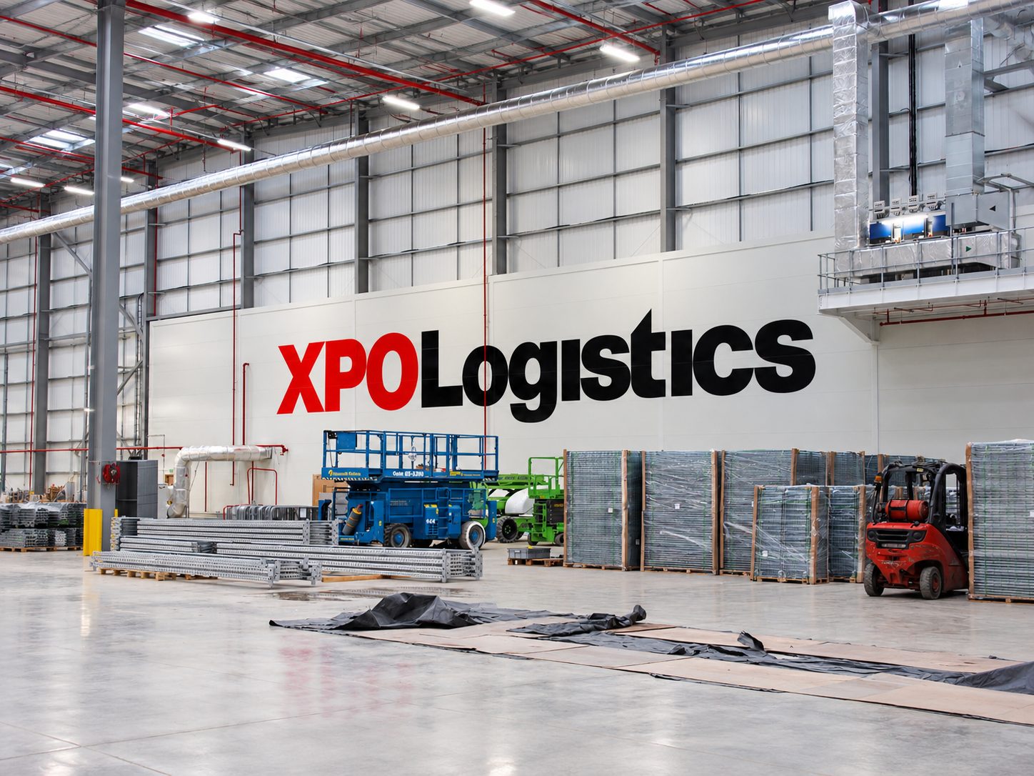 Warehouse interior with 'XPO Logistics' signage; pallets, forklift, and stacked materials ready for shipping.