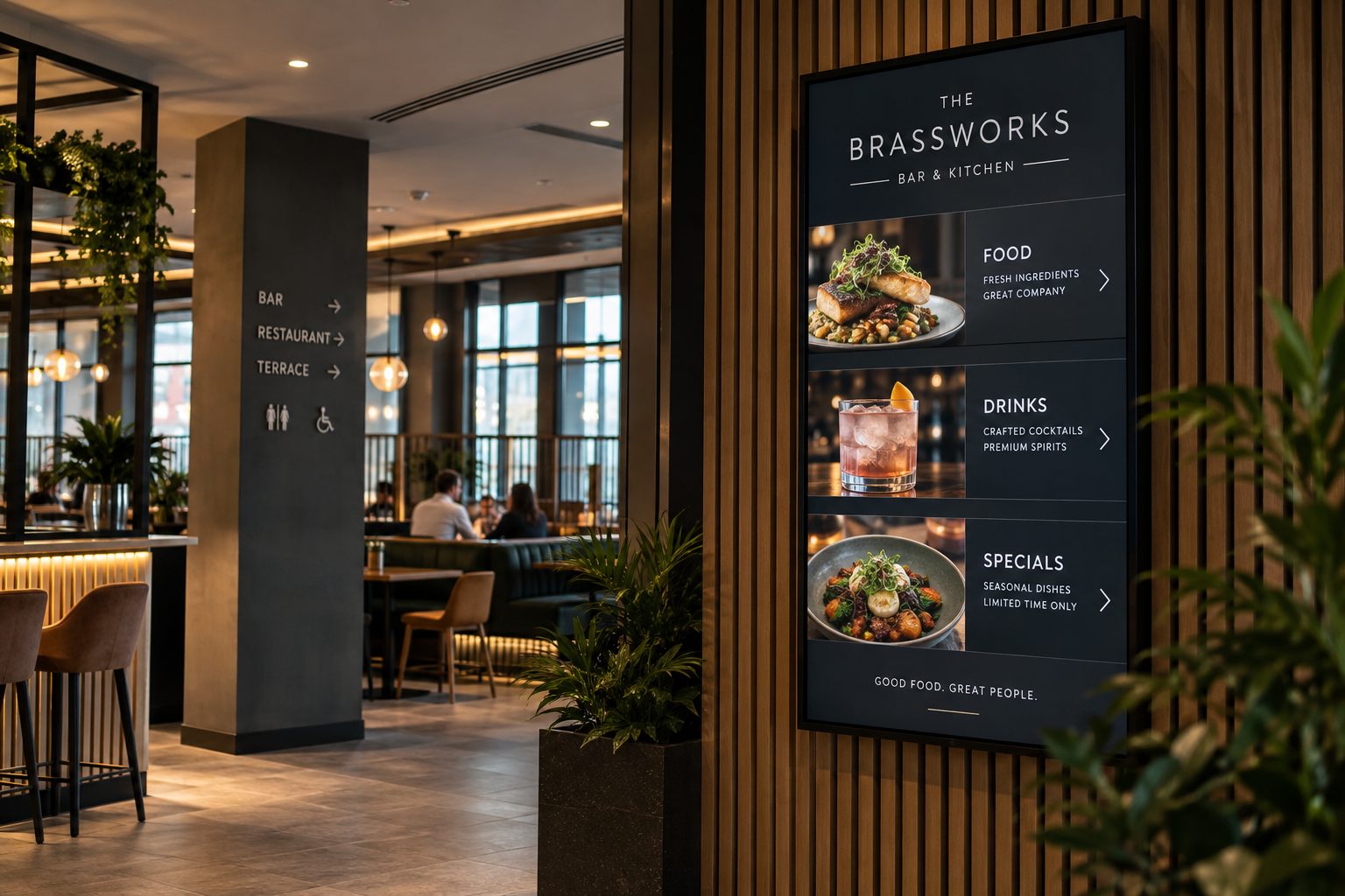 Modern restaurant interior with a tall digital menu board on a wooden slat wall showing Food, Drinks, and Specials, and diners seated in the background.