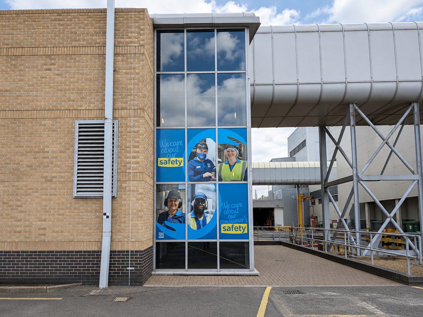 Brick building with a glass entrance displaying safety posters: 'We care about our safety'.