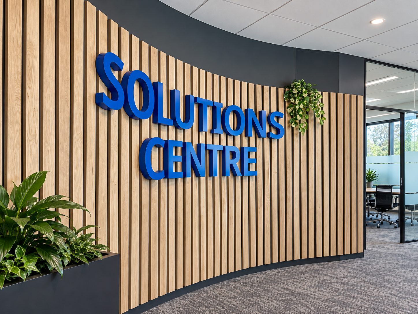 Curved wood-slat feature wall with bold blue 'SOLUTIONS CENTRE' lettering, plants, and glass-walled meeting room in a modern office entrance.