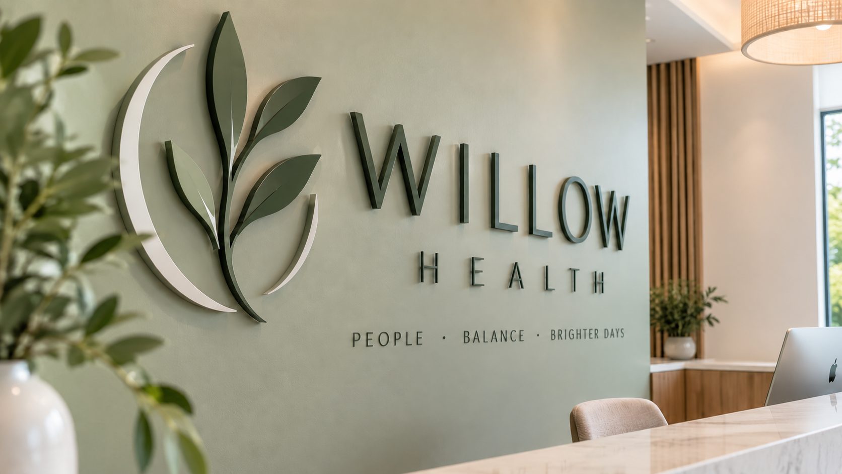Reception area with a green wall showing the Willow Health logo and the motto 'People · Balance · Brighter Days'.