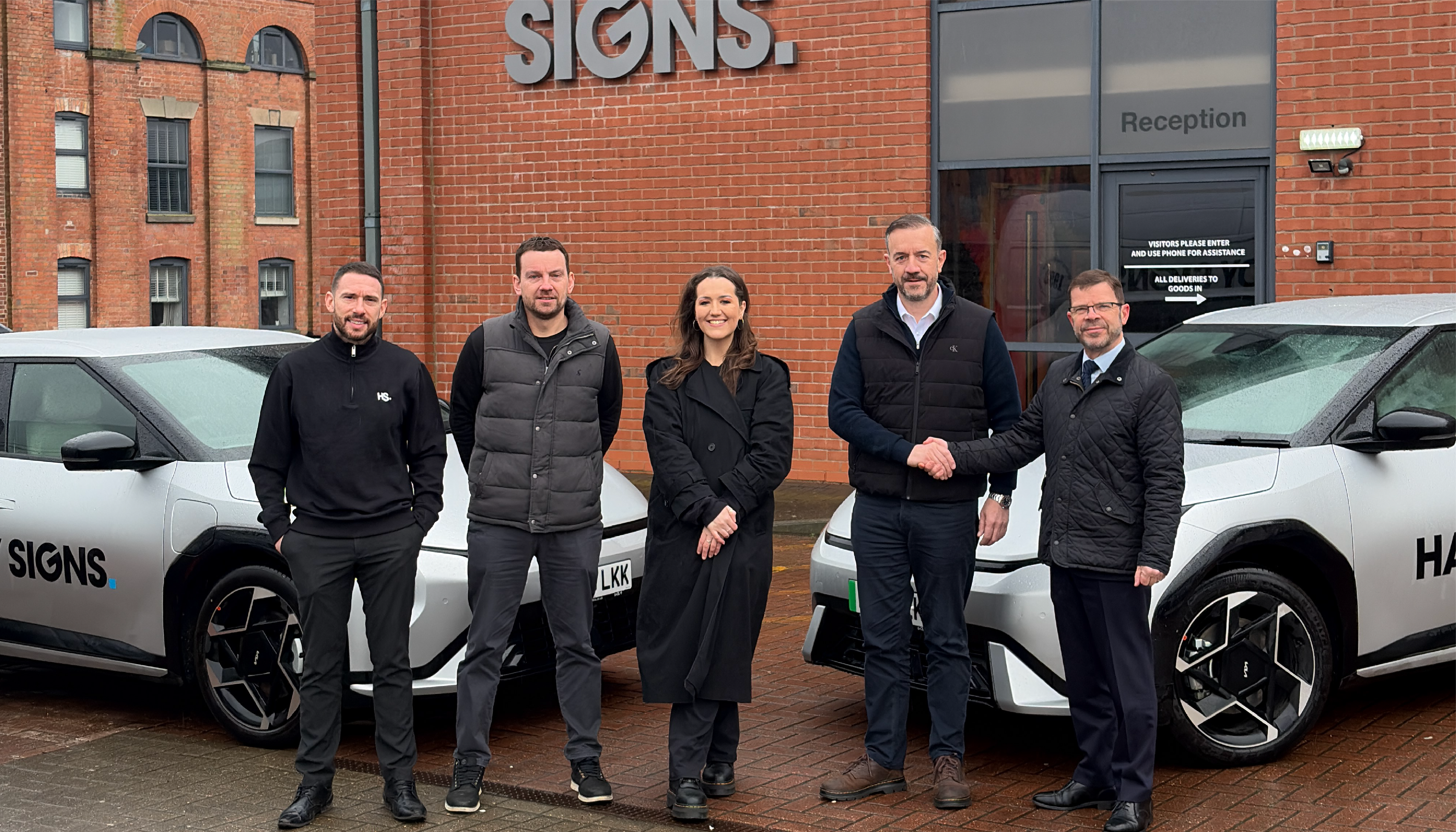 Scott Sudale, Tom Hardy, Blu Hardy, Nik Hardy and Dale Bywater standing next to two new EV cars from Burton KIA