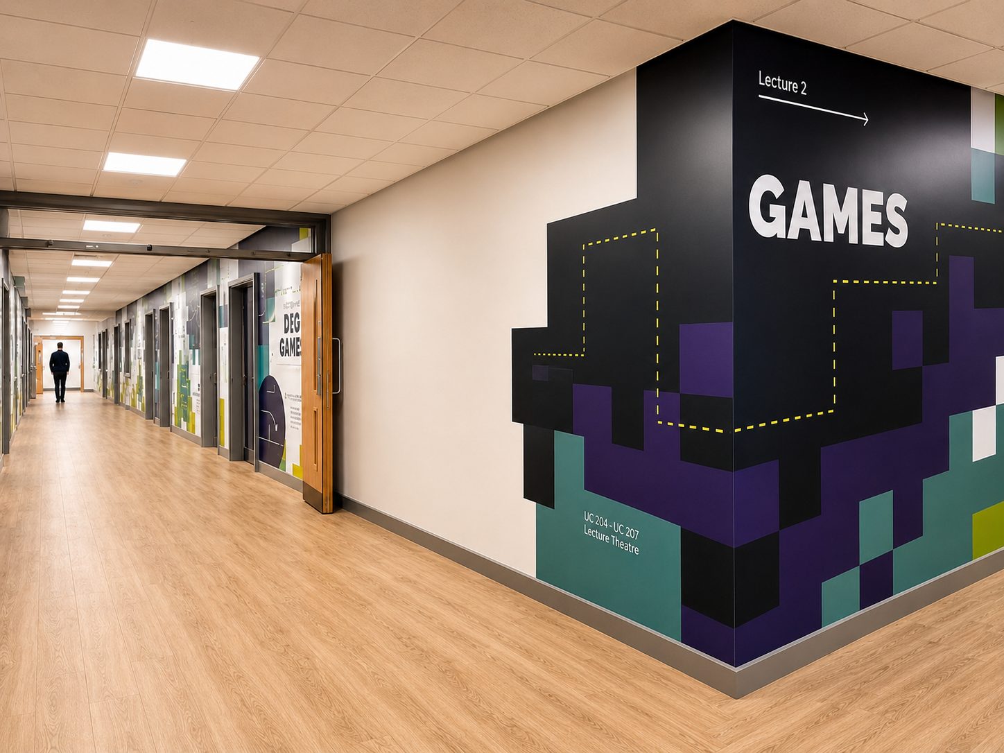 Long hallway with a colorful geometric mural on the right wall reading 'GAMES' and 'Lecture 2', a person walking in the distance.