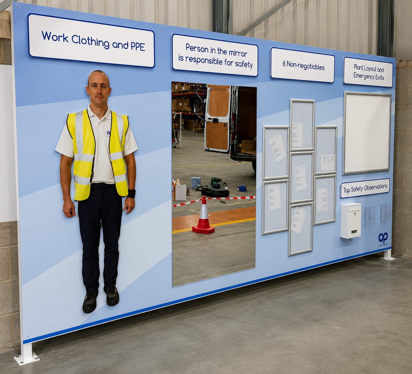 Worker in a high-visibility vest stands beside a safety display wall in a warehouse.