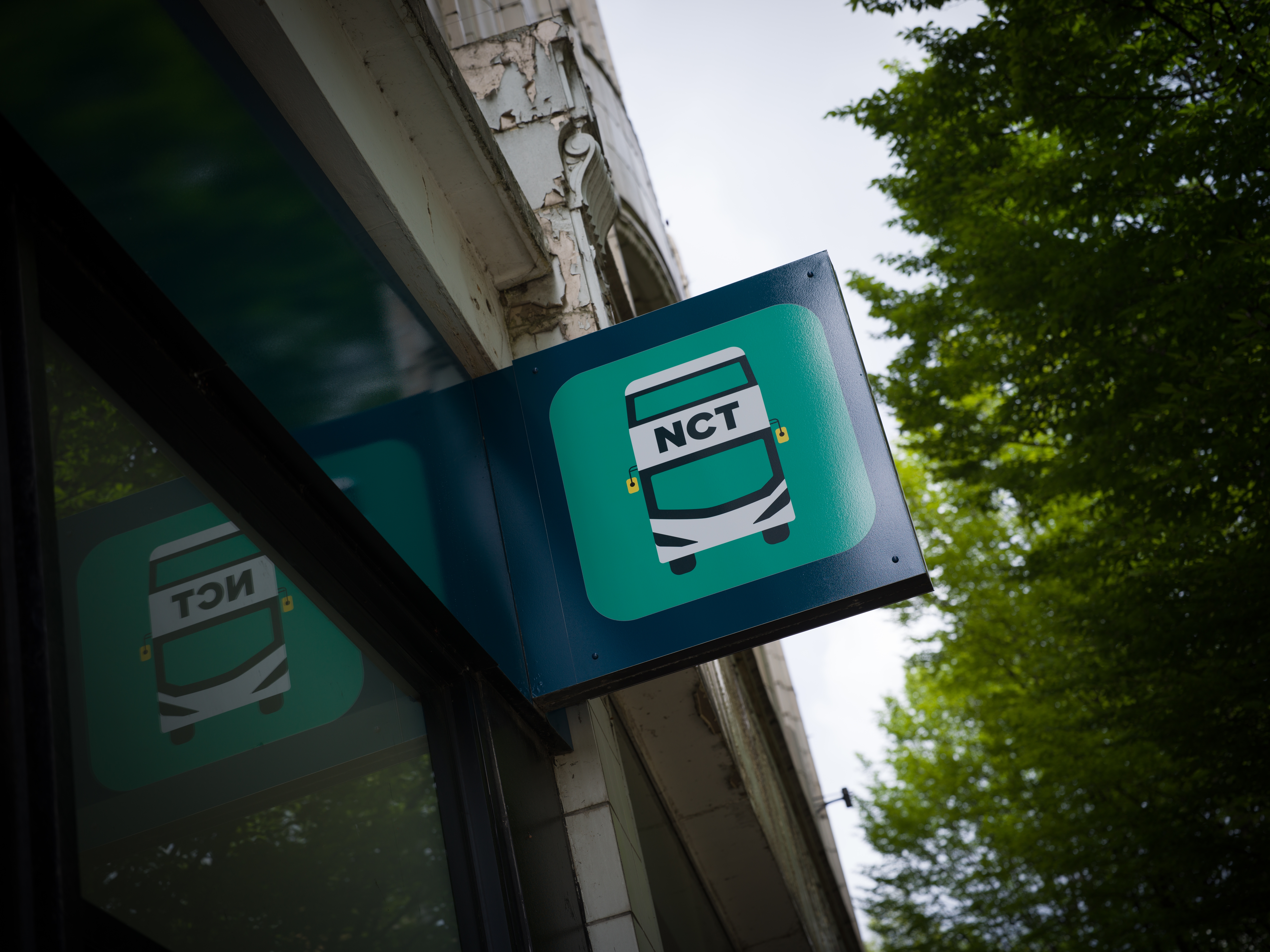NCT bus stop projecting sign mounted outside a building in Nottingham.